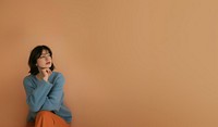 An attractive young adult woman with shoulder-length hair background blue contemplative.