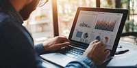 Businessman using a laptop charts business screen.