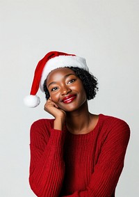 African woman wearing Christmas-themed and a Santa hat sweater happy expression.