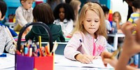 Caucasian girl in a classroom, young Caucasian girl drawing and coloring. Classroom with children. Student girl drawing and coloring in classroom. White student girl drawing in classroom.