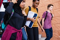 Diverse group of students, including a young woman in a hijab, a Black girl walking together. Students carrying backpacks and books, students heading to class. Diverse teenage students at school.