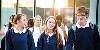 Group of teenagers, including boys and girls, in school uniforms. School uniforms worn by teenagers. Teenagers in school uniforms walking together. High school teenagers in school uniforms walking.