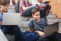 Group of boys using laptops and tablets on stairs. Boys with laptops, boys with tablets, boys studying. Young boys, technology, learning. Boys, laptops, tablets. High school boys with laptops.