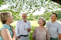 Group of diverse elderly friends enjoy park, smile and laugh. Elderly friends laugh and have fun outdoors, enjoy nature in park. Diverse group of elderly friends smile in nature, have fun in park