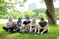 Group of diverse happy senior friends chat in park, green grass lawn. Diverse senior friends enjoy healthy relax lifestyle on grass. Healthy diverse senior group chatting, enjoy outdoor park activity