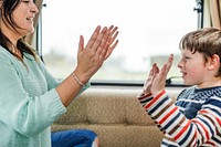 Mom and boy play a clapping game. Mom and son are smiling, enjoying their clapping game. The boy and his mom are bonding through play. Family time concept, woman playing with boy, mom 