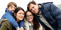 Happy Caucasian family outdoors, mother, father, son, and daughter. Family smiling, enjoying nature. Family trip outdoor nature, family at coast. Family hugging at coast nature outdoor.