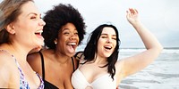 Three diverse plus size women enjoying the beach in swimsuits. Women smiling, beach in the background. Diverse women, swimsuits, beach, and smiles. Diverse friends travel to the beach.