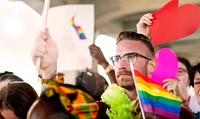 A diverse group of LGBTQ people at a pride parade. LGBTQ man with rainbow flag. LGBTQ man in pride parade, pride month celebration, LGBTQ man in pride parade, happy diverse people in pride parade