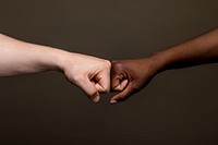 Close-up of a fist bump between diverse ethnic hands. Fist bump unity, friendship, and teamwork. Unity and friendship through a fist bump. Diverse people making fist bump gesture, multi ethnic people