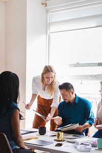 A diverse group of colleagues in a modern office. A woman and an Asian man collaborate on a project. The office environment is bright and professional. Marketing department collaborating on a project.