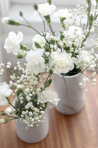 White flowers in white vases on a wooden table. The white flowers and white vases create a serene and elegant look. Flowers vase on the table, home decorations, white flowers in minimal room