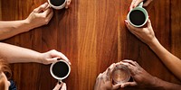 Diverse group of people having coffee. Top view of hands holding coffee cups. Coffee meeting with diverse hands. Coffee and conversation among diverse group of pleple. Diverse people drinking coffee