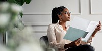 African American businesswoman reading a document. The woman, seated, is reading intently. African American businesswoman is in a modern office, African American CEO working in office