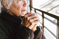 Elderly woman holds hands, wear Winter clothes. Elderly woman in WInter jacket holding hands. Close-up of elderly woman's hands, warming hands in Winter season. Elderly woman hold hands together