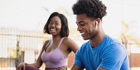 Smiling African American man and woman in activewear. The man in a blue shirt, the woman in a purple top. Both African American, both smiling, both in activewear. Fit athletes training outdoor.