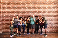 Diverse group of men and women at a gym. Standing confident by brick wall. Confident and strong, men and women in a fitness class at a gym. Working out together in a gym with brick wall.