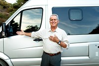 Happy senior man standing by a van. Senior man enjoying a trip with their van. Man posing by their van, with happiness and adventure. Senior man enjoying outdoors adventure and road trip.