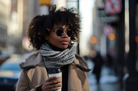An african american woman walking with a coffee on a city sidewalk photography portrait scarf.