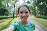 An asian athlete taking selfie while jogging in public park smile tranquility exercising.