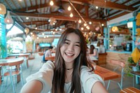 Asian influencer taking a selfie at the cafe restaurant portrait smile.