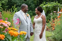 Black couple standing together in their wedding portrait smiling flower.