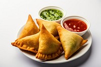 Samosa snack served with tomato ketchup and mint chutney food appetizer condiment.