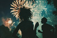 Fireworks with silhouettes of black people adult togetherness illuminated.