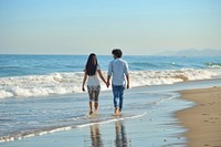 Indian young couple walking shorts beach.