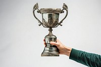 A hand holding up an aged trophy achievement innovation midsection.