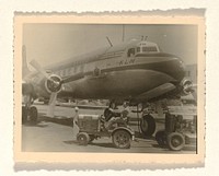 KLM-toestel The Flying Dutchman, met op de voorgrond een karretje voor het vervoer van bagage en andere spullen van en naar een vliegtuig (1947 - 1955) by anonymous
