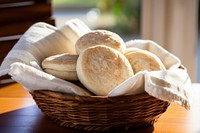 A basket of english muffins bread table food.