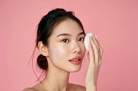 Cleansing her face skin with a cotton pad portrait adult woman.