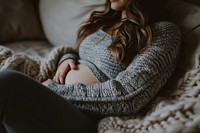 Pregnant woman lying in sofa sweater adult anticipation. AI generated Image by rawpixel.