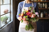 Woman in apron holding a bouquet of flowers plant adult store.