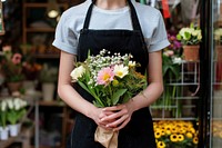 Woman in apron holding a bouquet of flowers plant store hand.