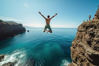 Athletic young man jumping off a rocky diving vacation summer.