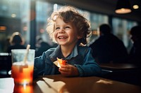 Happy kid eating in a restaurant laughing portrait smile.