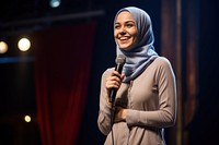 Young Muslim woman speaker on professional stage microphone smiling adult.