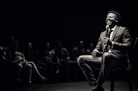 Black man speaker on professional stage microphone audience sitting.