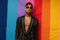 Cool LGBT young Latin man with fashionable clothing style full body on colored background sunglasses necklace jewelry.