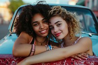 Woman with arm around female friend leaning on car smile togetherness affectionate.