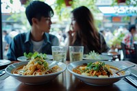 Thai man and woman dinner Tom Yum Goon restaurant lunch table.