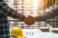 Two architects people shaking hands in front of yellow hard hats on desk handshake hardhat adult.