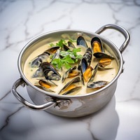 Mussels in a creamy white wine garlic sauce in stainless steel pan seafood meal dish.