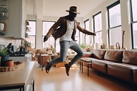 Black man dances in the living room footwear jumping architecture.