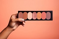 Eyeshadow palette on hand cosmetics medication lipstick.