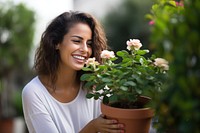 Woman and a rose plant pot laughing outdoors smiling.