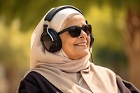 Qatari senior woman headphones listening glasses.