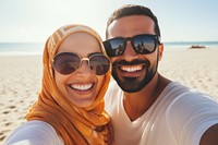 Middle eastern man and woman taking a selfie at the beach sunglasses portrait outdoors.